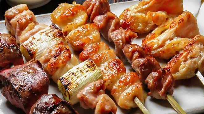 つやのある焼鳥を数本盛り付けた黒い皿